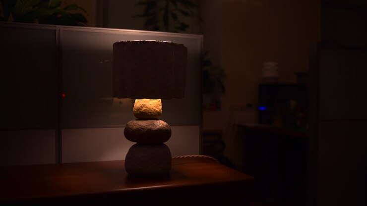 Dempede lampe med teksturert skjerm som kaster et varmt skjær, nattbordscene, myk omgivelsesbelysning, koselig nattestemning. Media