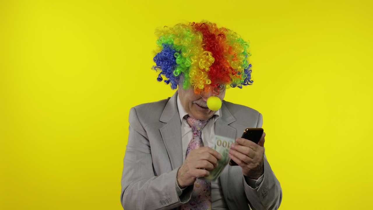 Klovneforretningsmand, iværksætterchef modtager pengeindkomst, mens han bruger sin smartphone.