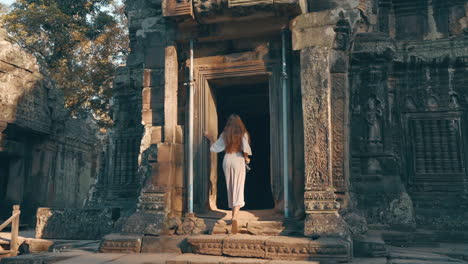 following a young woman as she walks through ancient carved temple ruins of ta prohm, cambodia