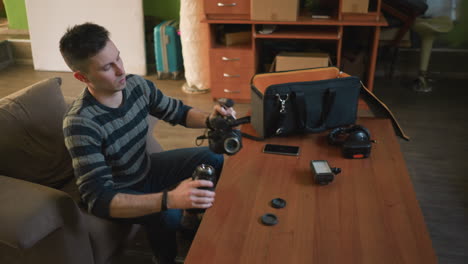person working with video camera, adjusting lens and microphone on table. camera equipment and accessories, bags, lighting, tech tools, indoor workspace, content creation setup