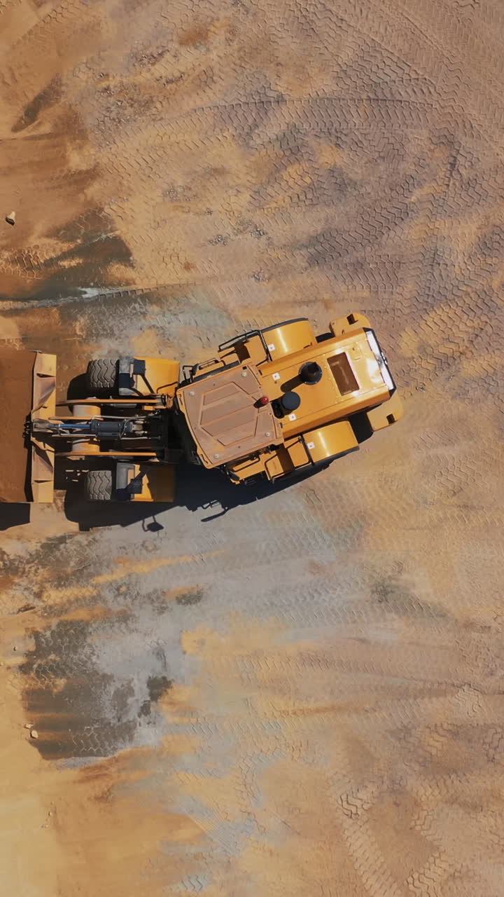 Road under construction. Top view of heavy machine working in construction site Vertical video