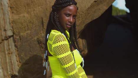 close-up foto do rosto de uma menina negra com cabelo trançado natural com um penhasco como pano de fundo