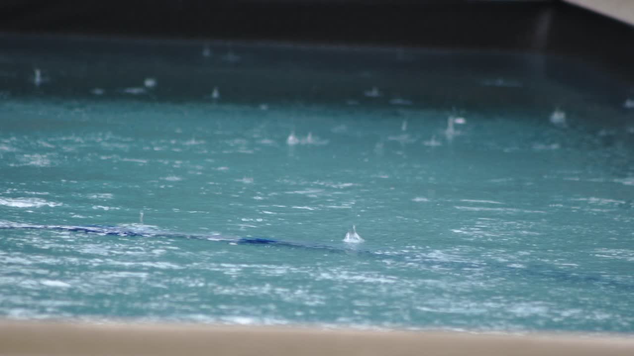 Pool showing rain with raindrops during inclement weather for swimming, close-up