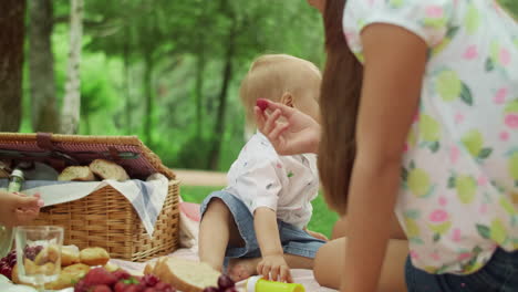 Young-mother-with-children-sitting-on-blanket-in-park.-Family-having-picnic