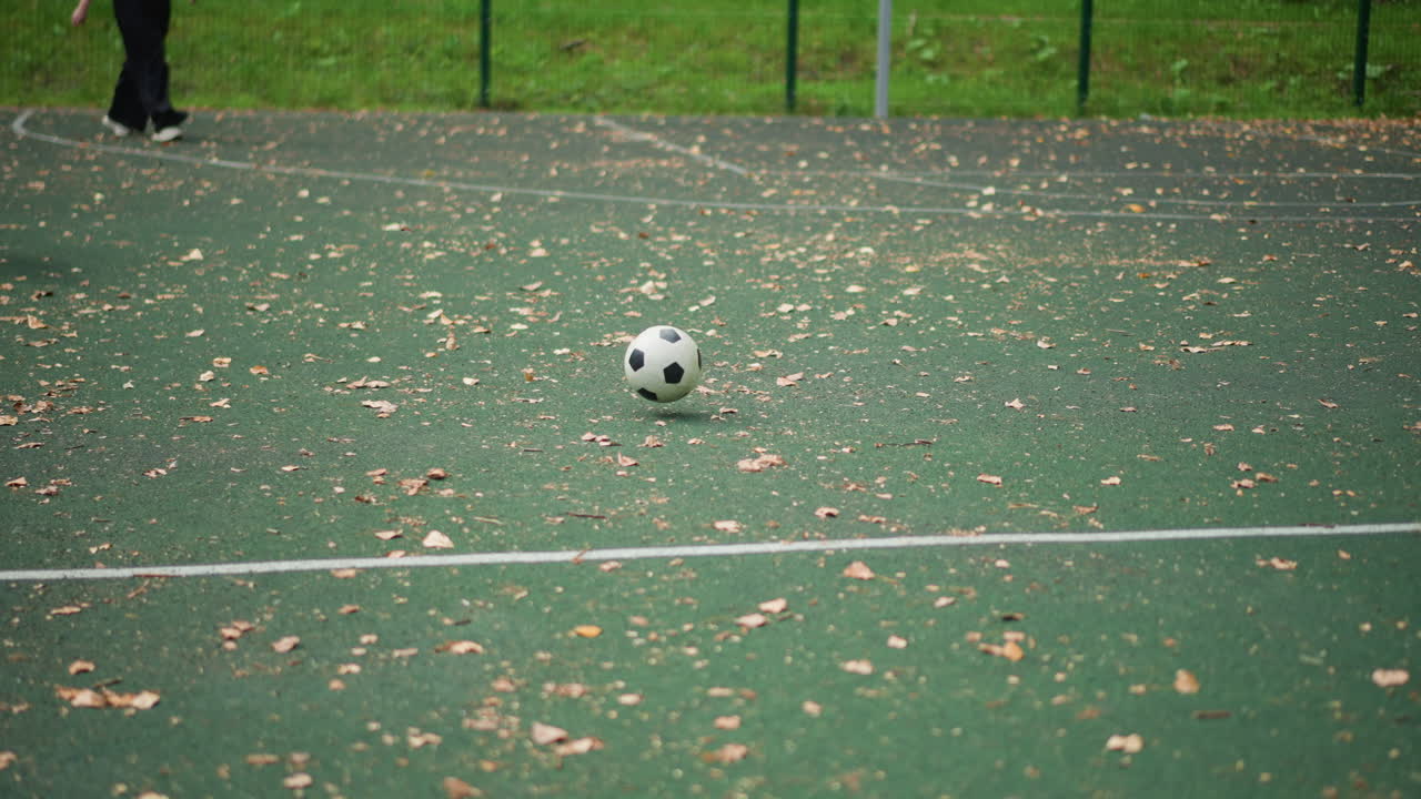 Young Boy Follows Moving Ball, Youthful Child Attentively Watches Football Roll Through Autumn Leaves, Young Boy Eagerly Observes Soccer Ball As It Rolls Through Autumn Leaves Outside