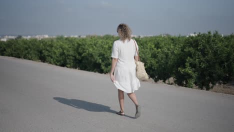 woman walking on a road through a fruit orchard