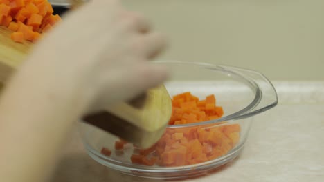 female housewife hands puts pieces of sliced carrot into salad plate