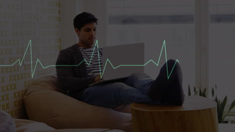 animación de un cardiógrafo sobre un hombre de negocios biracial usando una computadora portátil