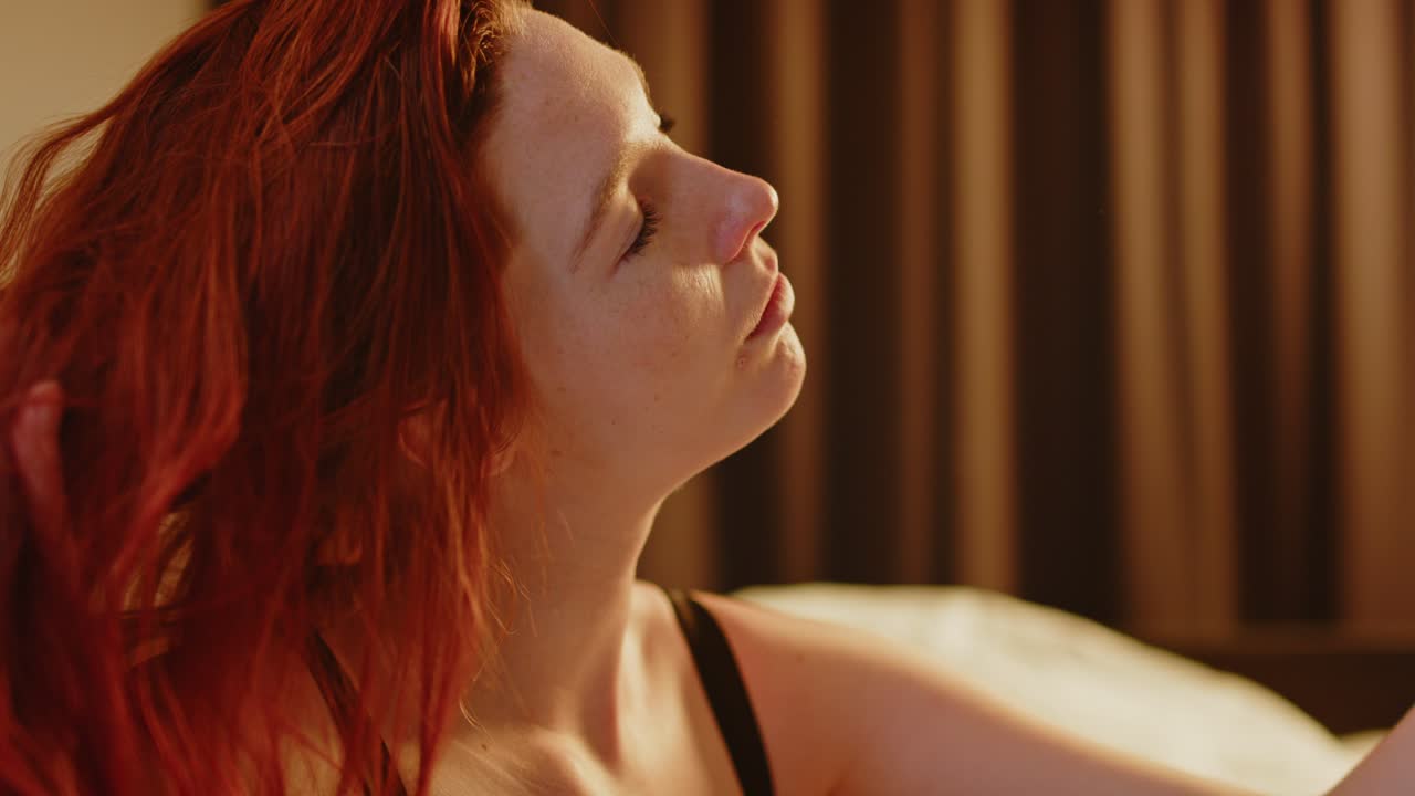 una hermosa mujer joven sacudiendo la cabeza y tirando su largo cabello rojo