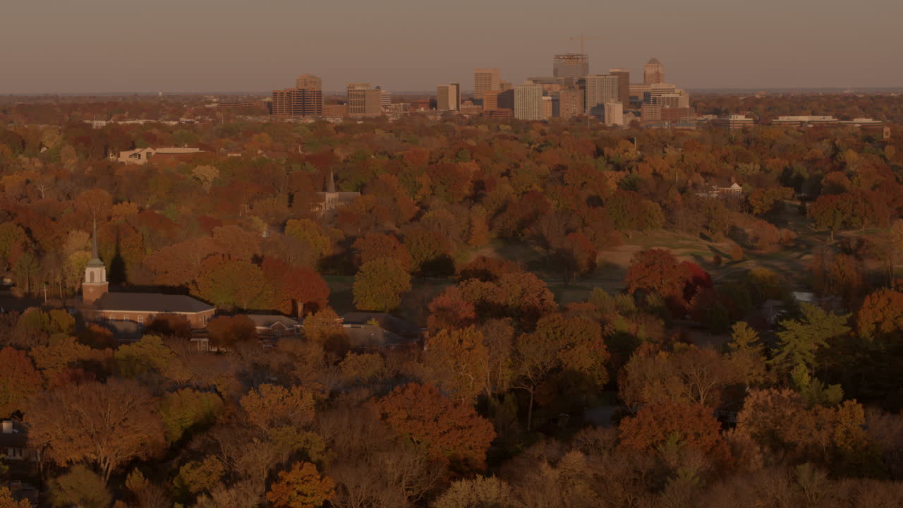 empuje aéreo hacia una pequeña iglesia, parque y horizonte de la ciudad en otoño