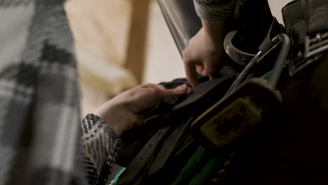 expert jockey preparing black horse for riding at the stable