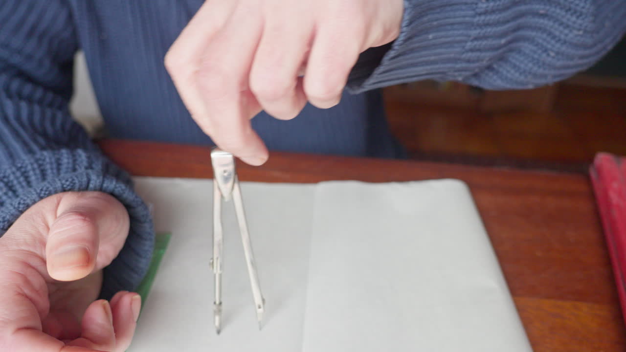 Medium shot of hands using a compass to draw a precise circle, emphasizing accuracy, technical skill, and geometric design work