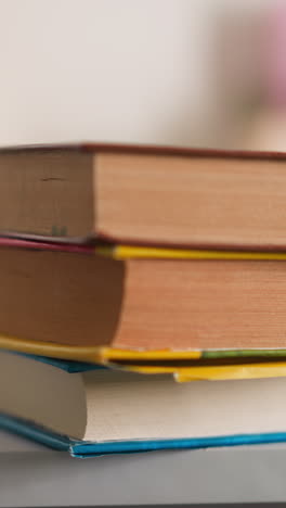 little girl puts textbooks heap on desk with school supplies at home closeup. schoolgirl prepares literature for homework lesson at table in children room