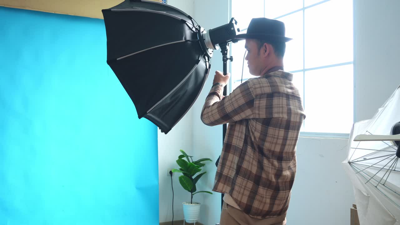 Jonge fotograaf die belichting instelt voor een fotoshoot in de studio.