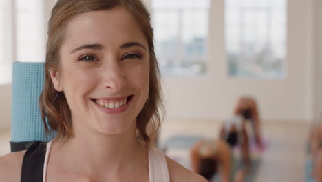 Retrato-Hermosa-Mujer-Caucásica-De-Yoga-Sonriendo-Con-Confianza-Disfrutando-De-Un-Estilo-De-Vida-Saludable-Con-Gente-Practicando-En-El-Fondo-Del-Gimnasio