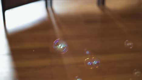 burbujas de jabón grandes y pequeñas que se elevan desde el parquet de madera marrón