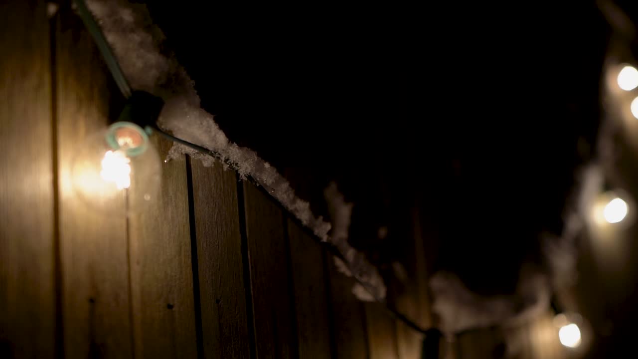 luces de patio al aire libre colgadas en una valla, cubiertas de nieve, sartén a cámara lenta