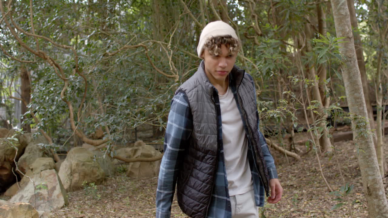 Young man exploring forest, wearing warm clothing, enjoying nature walk