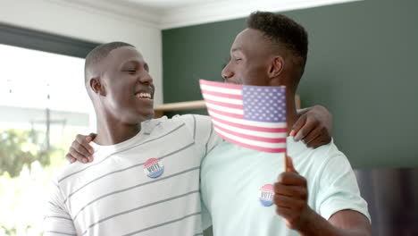 amigos afroamericanos celebran en casa, con insignias de voto con banderas estadounidenses