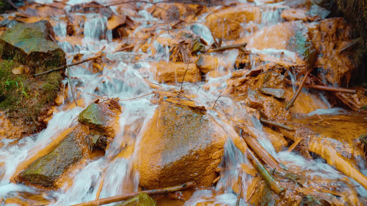 Beautiful orange color rocks in a sulfur spring waterfall. iron-containing creek water.