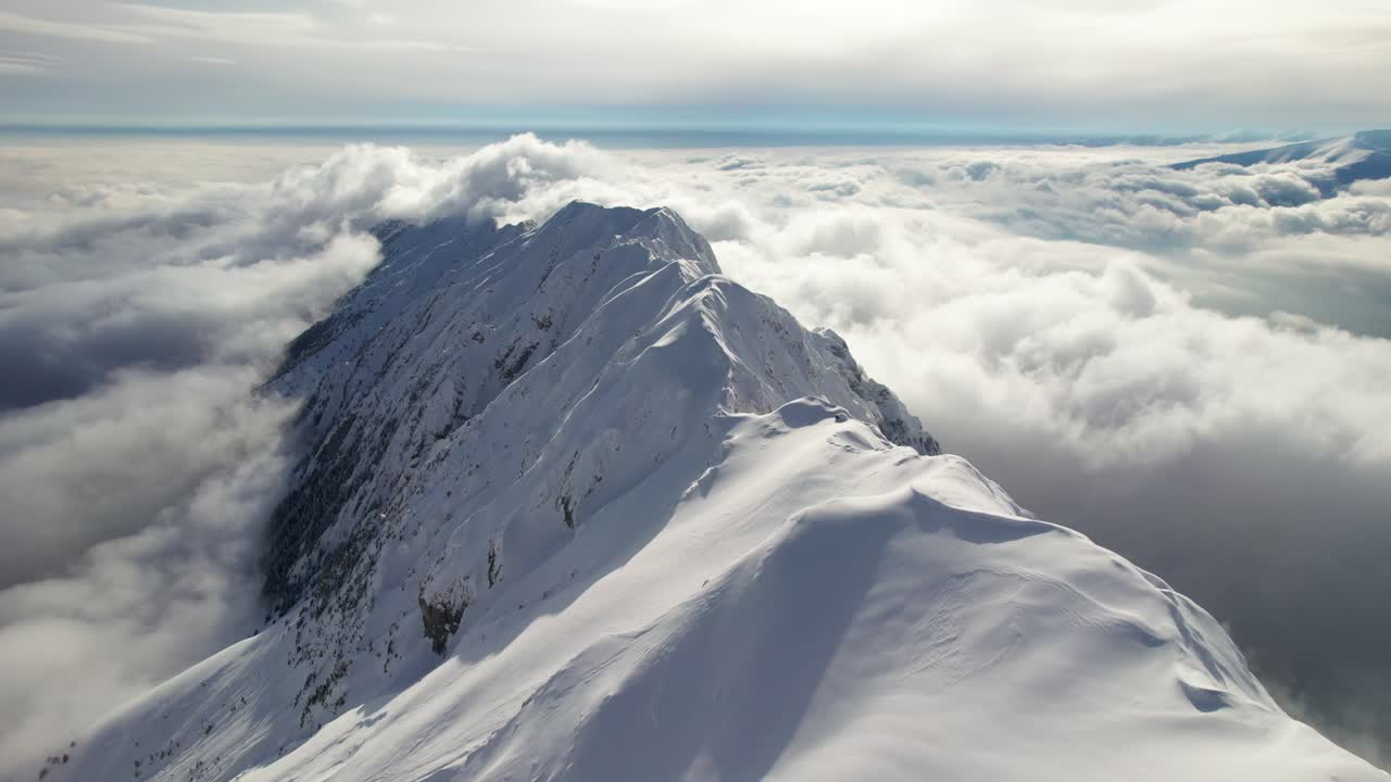 las montañas nevadas de piatra craiului alcanzan su punto máximo a través de un mar de nubes bajo un cielo azul, vista aérea