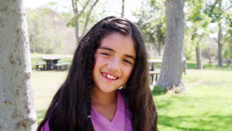 Slow-Motion-Portrait-Of-Young-Girl-With-Backpack-In-Park-Smiling-At-Camera