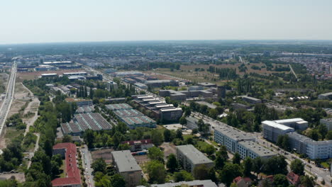 Forwards-fly-above-industrial-or-logistic-park-in-suburbs.-Buildings-with-rows-of-skylights-on-roof.-Flat-landscape.-Berlin,-Germany