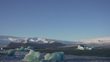 Iceberg-in-jokulsarion-lagoon-with-mountains-and-snow,-Iceland