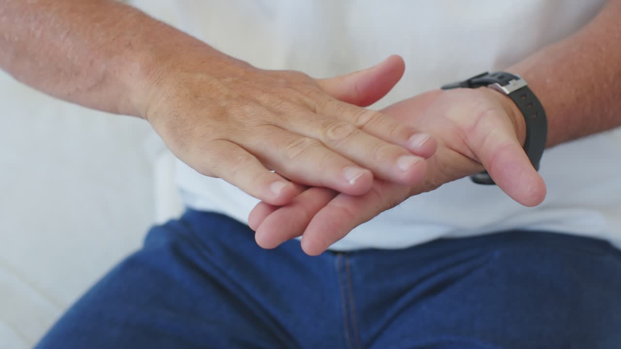 Man's hands are pressing pump, dispensing cream and rubbing lotion to moisturize palms on couch