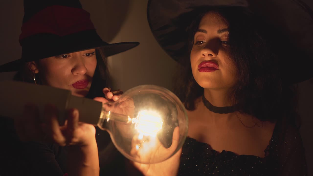 Two Witches Examining a Glowing Light Bulb
