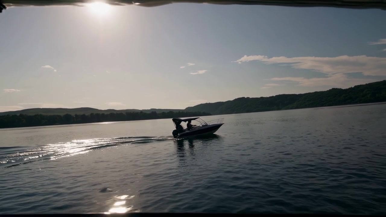Motoscafo che naviga su un lago con il riflesso del sole