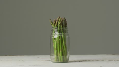 video of fresh asparagus stalks in jar over grey background