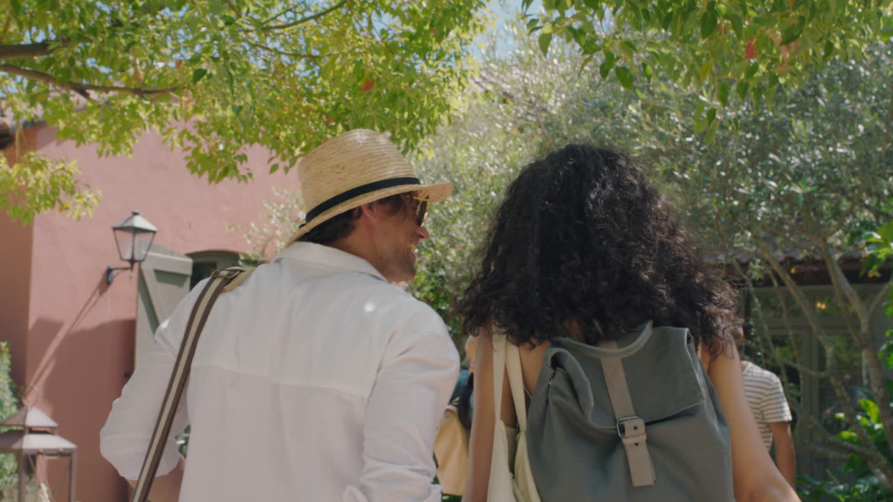 coppia di viaggiatori che arrivano alla villa dell'albergo con gli amici guardando la bellissima casa di campagna eccitati per le vacanze turisti che si godono le vacanze estive insieme filmato 4k