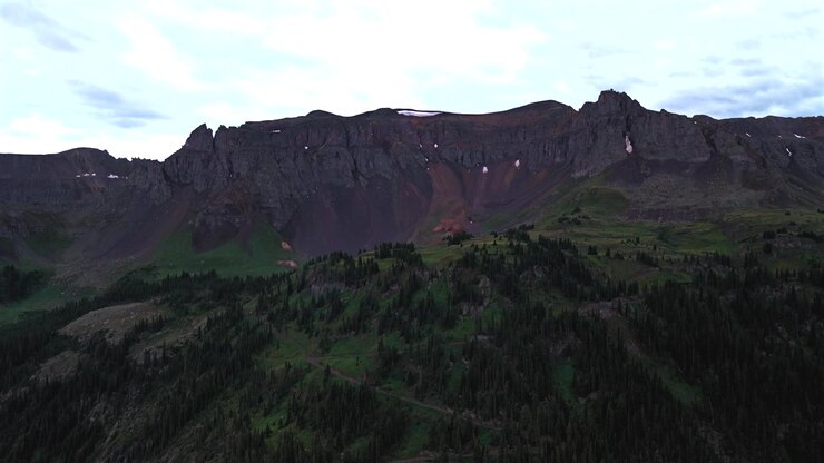Yankee Boy Basin neve alpina alta Blue Lakes Telluride Ouray Colorado meridionale vista aerea con drone Montagne Rocciose Catena del San Juan paesaggio strada sterrata 4x4 a trazione integrale estate nuvole basse e piovose pomeriggio in avanti.