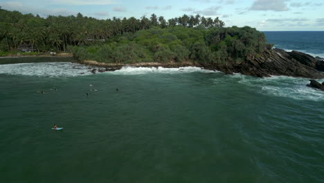 estableciendo una toma aérea de drones de la bahía de hiriketiya con surfistas flotando en el sur de sri lanka