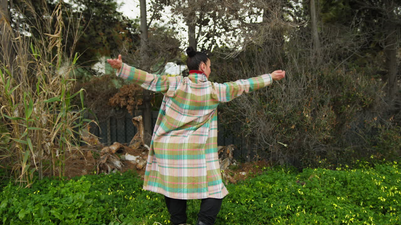 Woman Dances To Slow Music In A Park Near Plants In Nature
