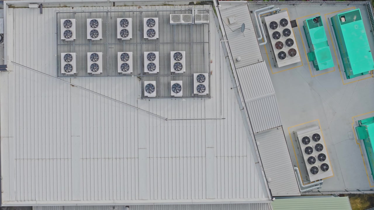 Drone shot of a modern data centre rooftop filled with large HVAC and cooling units. Clean geometric lines, metallic textures, and diffuse daylight highlight this secure facility's infrastructure.