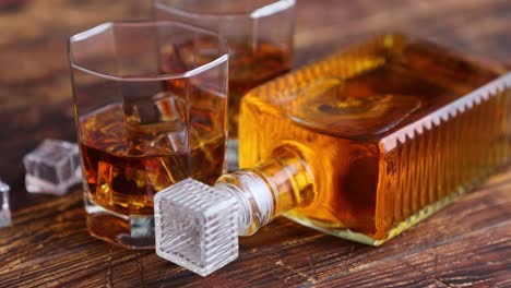 bottle of whiskey with two glasses placed on rustic wooden table