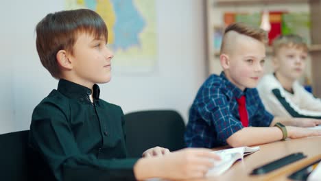 elementary school children study. learning process in the classroom. boys sitting at desk and answering at the lesson. back to school.