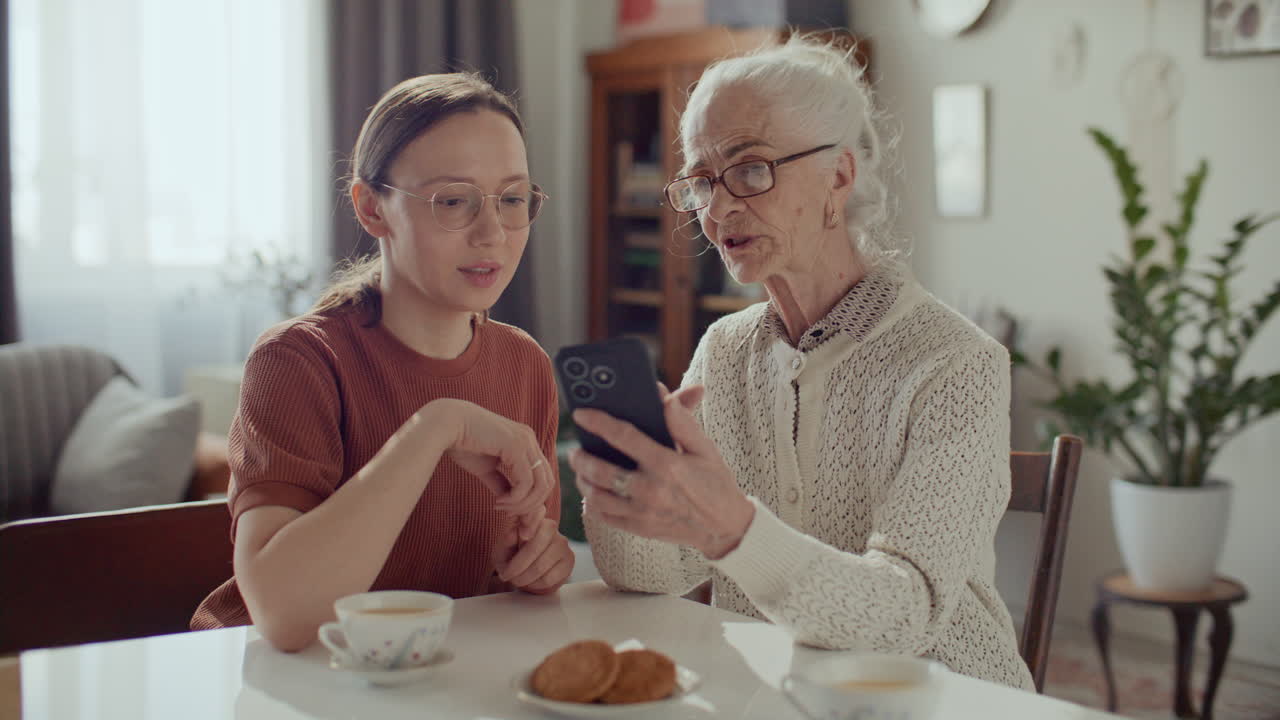 Anziana donna che guarda foto sullo smartphone insieme alla nipote