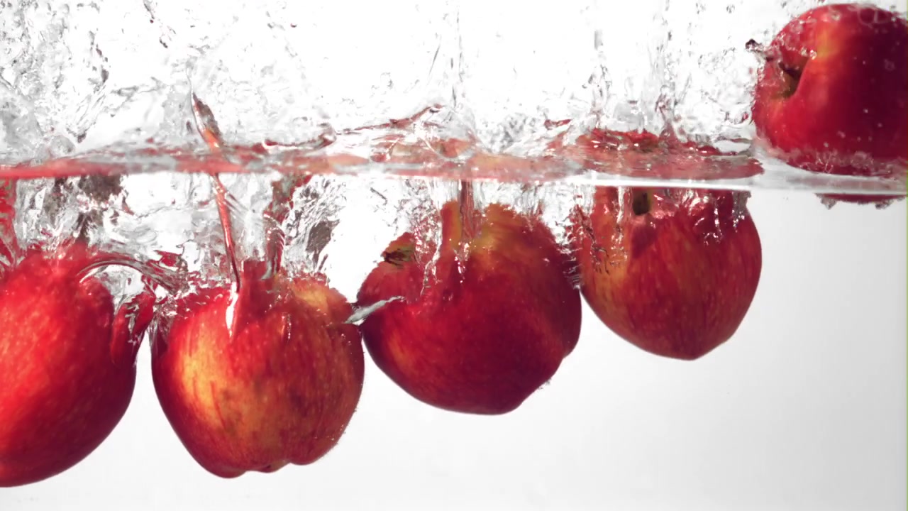 Mele rosse fresche che schizzano in acqua limpida