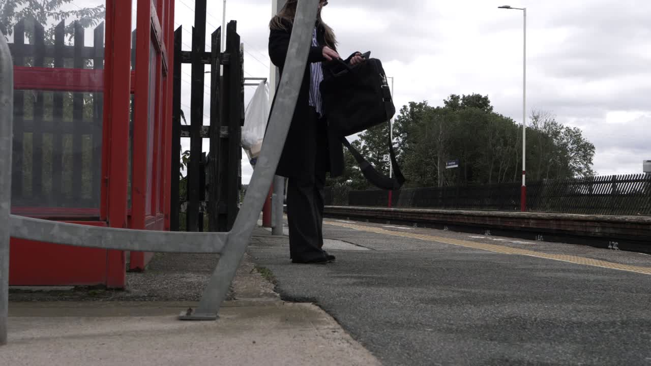 Business woman looking in briefcase at railway station wide shot
