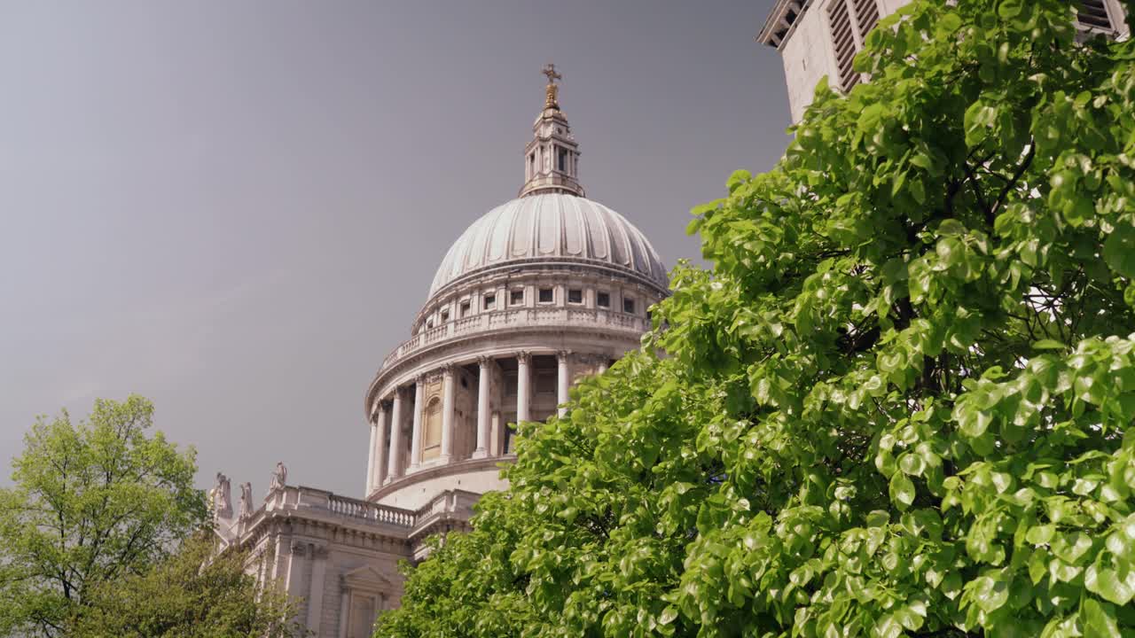 Beautiful view of famous St. Paul church's dome with trees in the foreground during daytime as the wind slowly blowing the leaves