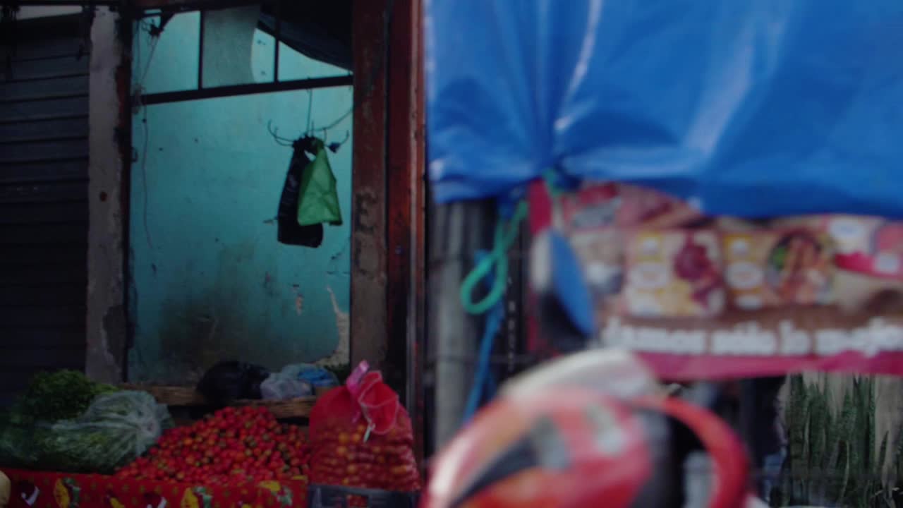 Street view fruit market Zone 18 Guatemala City, man in apron unfolding newspaper