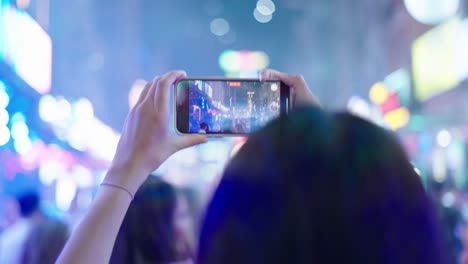 person taking video of a night street scene