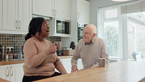 elderly man and caregiver having coffee in kitchen