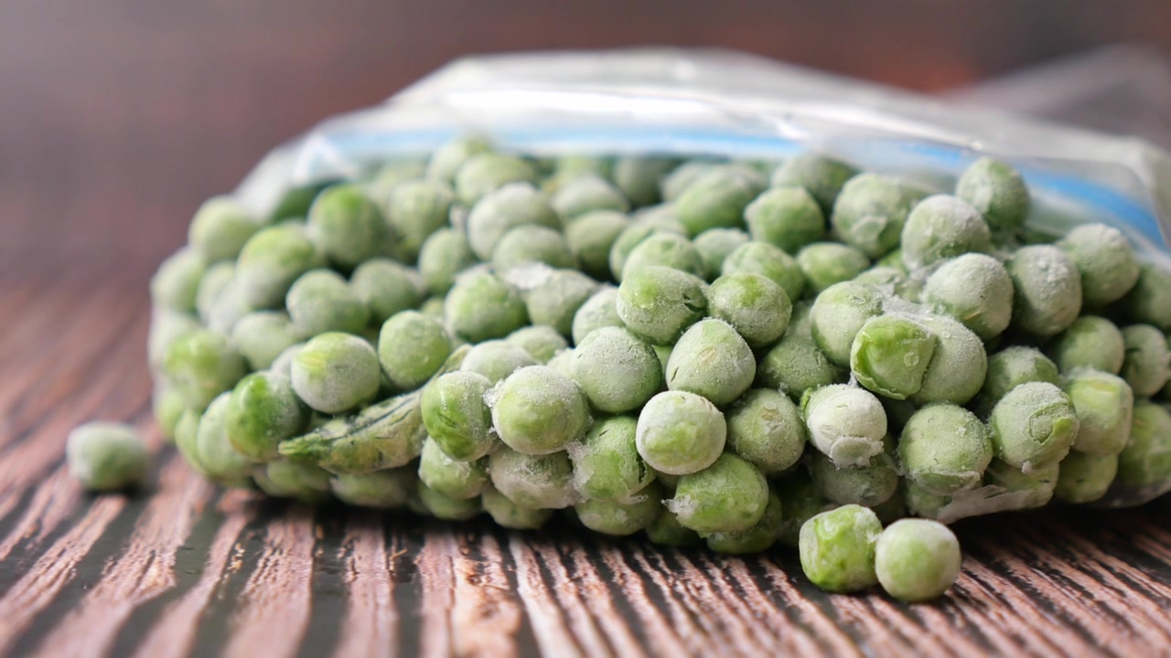 Frozen Green Peas in a Plastic Bag on a Wooden Table