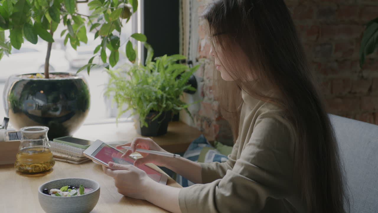 Young Woman Working on a Digital Tablet in a Cafe