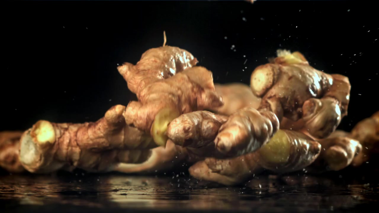 Fresh Ginger Roots Falling and Splashing on Wet Black Surface in Slow Motion