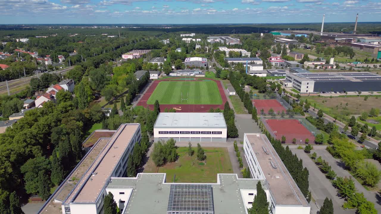 sports facilities at Hennigsdorf high school, including a soccer field, running track and other buildings in residential areas. Perfect aerial view flight overflight flyover drone